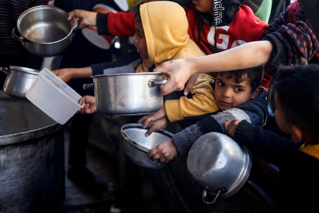 Palestinian children in Rafah wait to receive food distributed by a charity kitchen amid severe food shortages of food supplies.